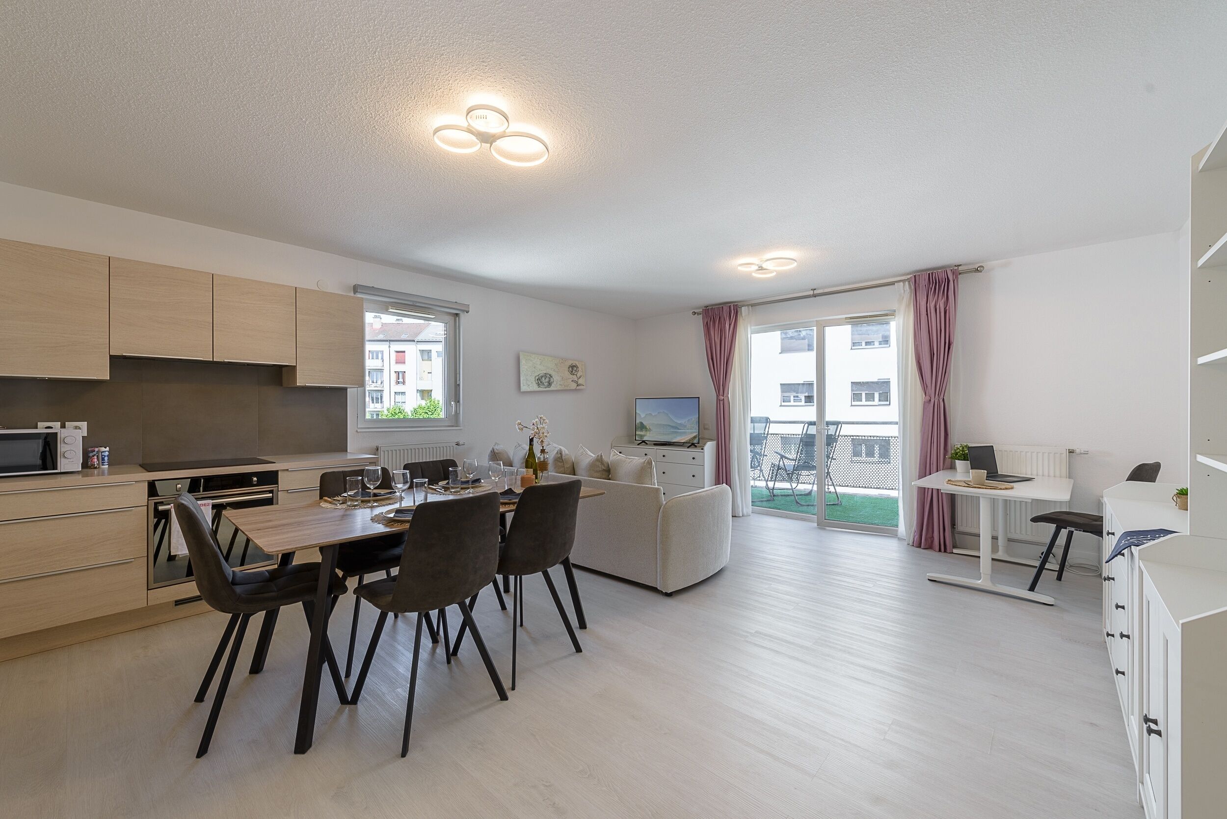 Eine moderne Wohnung mit Küche, Essbereich und einem Balkon mit Blick.