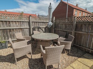 A patio with wicker furniture, a round table, and a wooden fence. - 3 Railway Terrace (Bridlington)