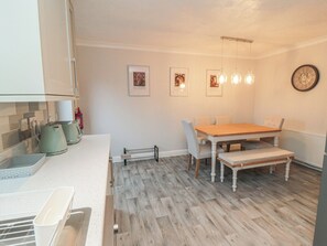 A kitchen with a wooden table and chairs, a radiator, and framed pictures on the wall. - 3 Railway Terrace (Bridlington)