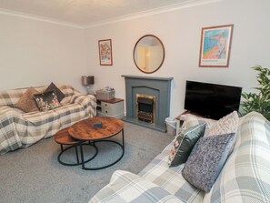Ein Wohnzimmer mit einer Couch, einem Couchtisch, einem Kamin, einem Fernseher und einem Spiegel.
