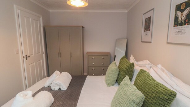 Ein Schlafzimmer mit Bett, Kleiderschrank, Schminktisch und einem gerahmten Bild an der Wand.