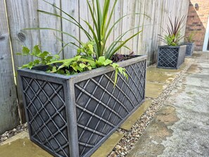 A planter box with plants, a wooden fence, and a concrete pathway. - 3 Railway Terrace (Bridlington)