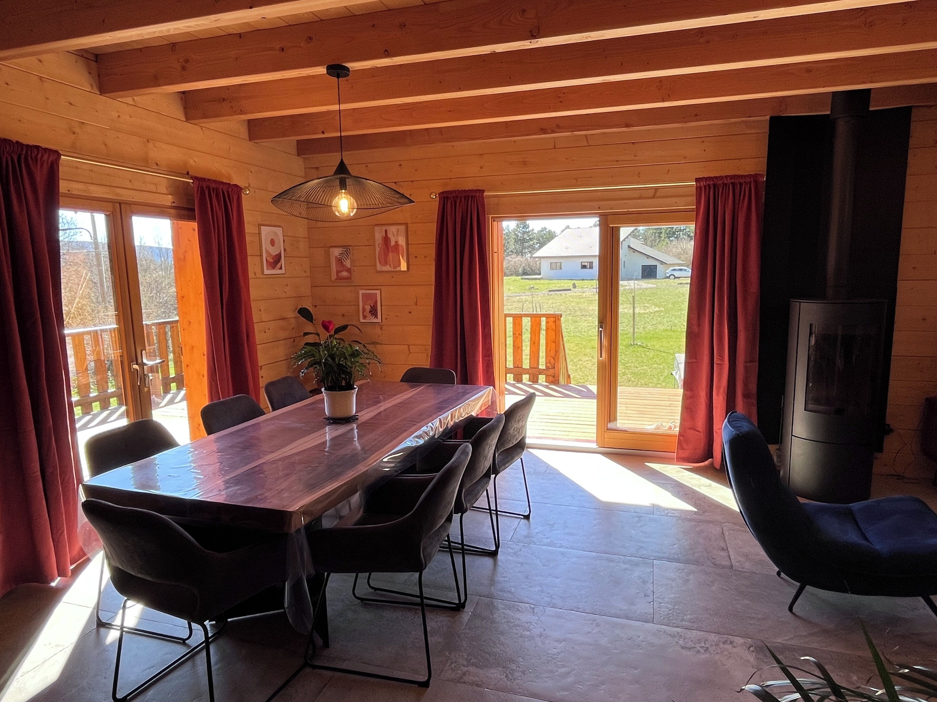 Eine Holzhütte mit Esstisch, Stühlen, einer Topfpflanze und einem Kamin.