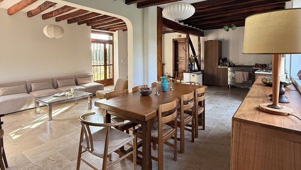 Un salón amplio con una mesa de comedor de madera, un sofá y una cocina al fondo.