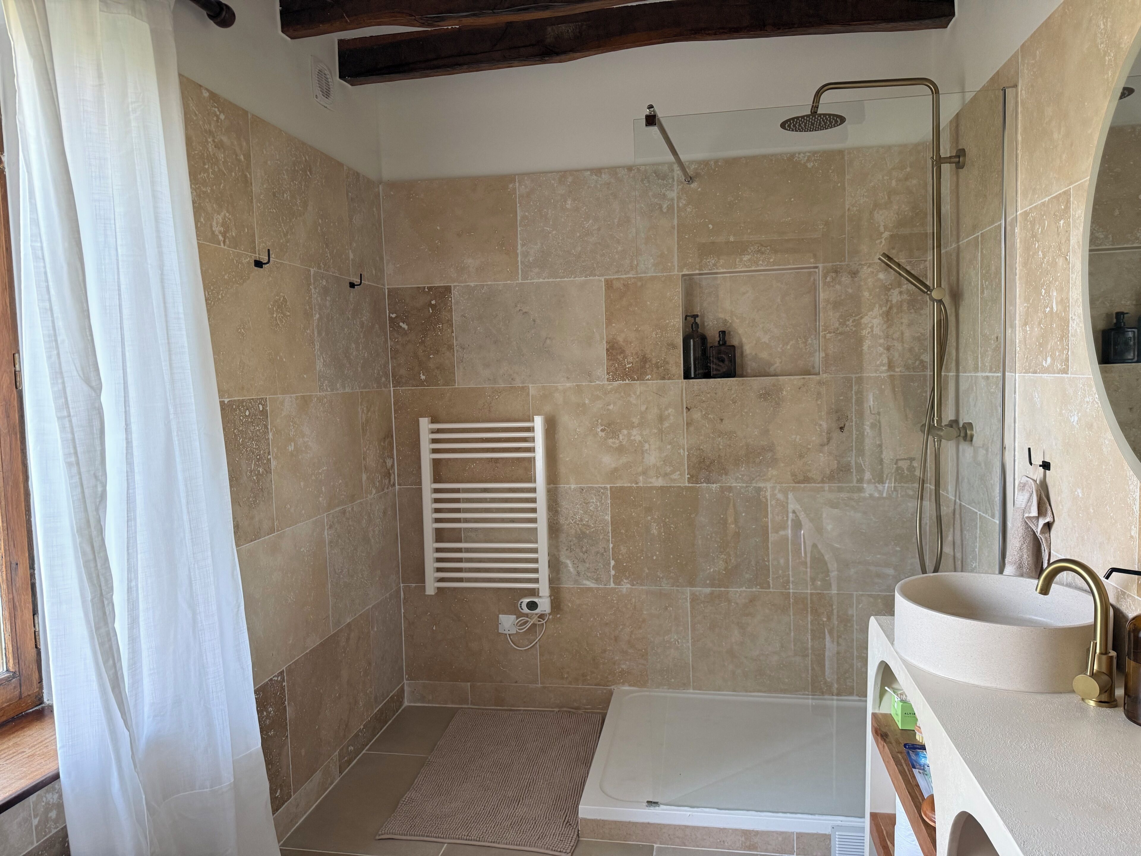 Un baño con ducha, lavamanos y un perchero para toallas.