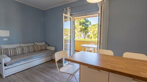 Une pièce comprenant un canapé, une table à manger, des chaises et une porte-fenêtre coulissante donnant sur un espace extérieur.