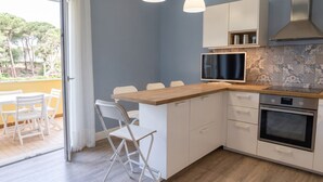 Une cuisine moderne avec un plan de travail en bois, des armoires blanches, un four encastré et un téléviseur.