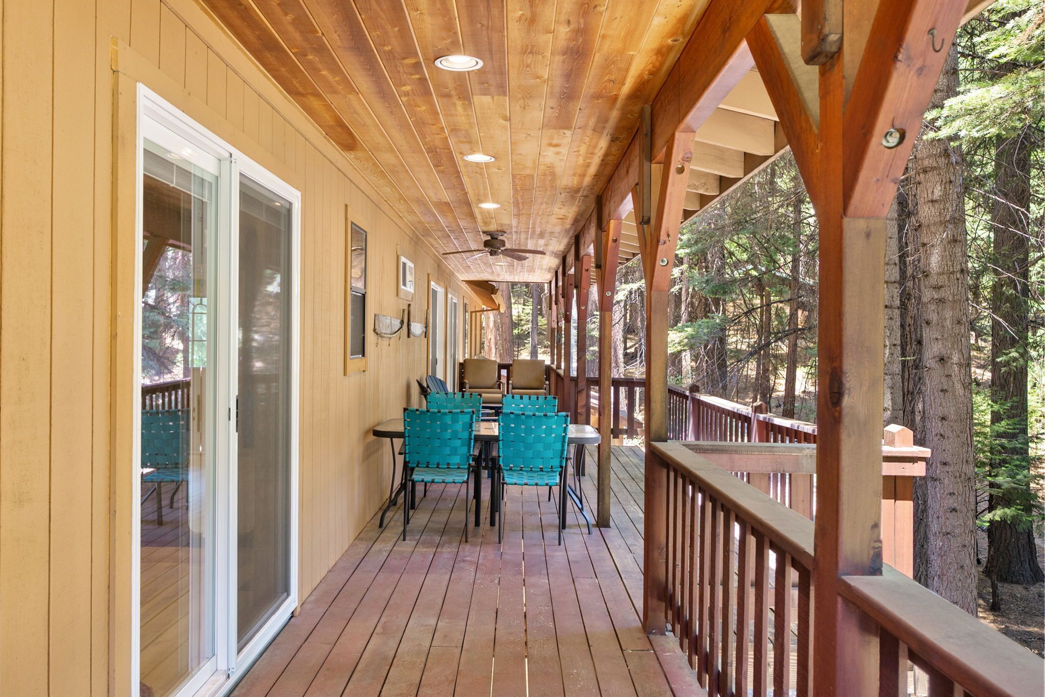 Una veranda in legno con tavolo e sedie, circondata da porte vetrate e ringhiere in legno.