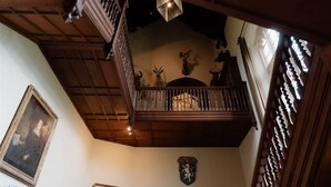 A wooden balcony with a railing, a chandelier, and mounted animal heads on the wall.