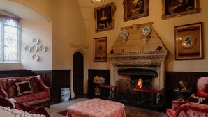 A traditional room with a fireplace, red upholstered furniture, and decorative plates on the wall.
