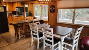 Een houten interieur met een keuken, een eethoek en grote ramen.