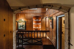 A wooden interior with a bench, a shelf with decorative items, and a framed picture.