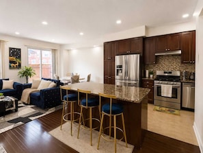 A modern kitchen with dark wood cabinets, stainless steel appliances, and a granite countertop.