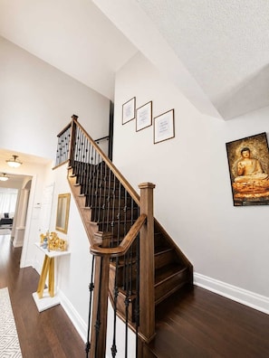 A staircase with wooden railings and a handrail, leading to an upper floor.