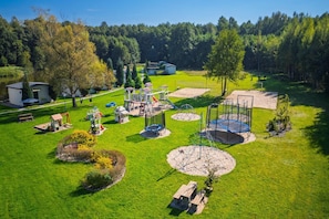 An aerial view of a park with playground equipment, a small house, and a pond. - Comfortable Holiday Home no. 2B With a Fireplace (Darlowo)