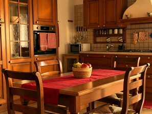Eine Küche mit Holzausstattung, einer Mikrowelle, einem Backofen und einem Esstisch mit Stühlen.