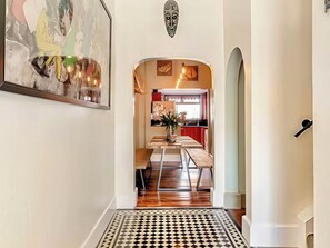 A hallway leading to a dining area with a checkered floor, a painting on the wall, and a decorative wall piece above the door. - Tapestry House (Bridlington)