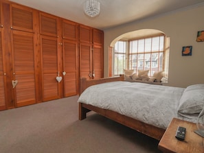 Ein Schlafzimmer mit einem großen Bett, einem Holzschrank und einem Fenster mit Jalousien.