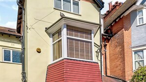 Une maison d’angle avec une baie vitrée, une façade rouge et une cheminée en briques.