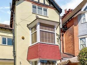 Ein Eckhaus mit Erker, roter Fassade und Backsteinschornstein.