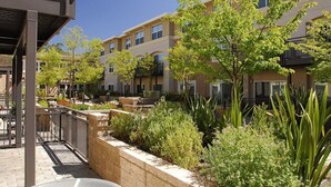 Un edificio residencial de varios pisos con balcones, una zona de estar al aire libre techada y jardines ajardinados.