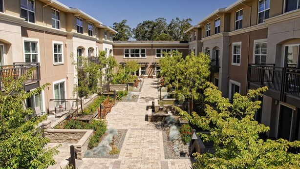 Un patio con un camino central, rodeado de edificios de varios pisos con balcones y ventanas.