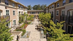 A courtyard with a central pathway, surrounded by multi-story buildings with balconies and windows. - Stylish 1BR Stay in Prime Location at Millworks (Novato)