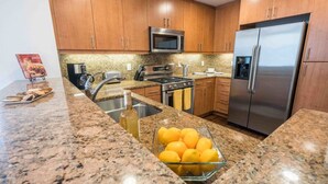 Una cocina con encimeras de granito, electrodomésticos de acero inoxidable y armarios de madera.