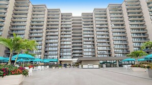 Een hotel met meerdere verdiepingen, balkons, buiten zitplaatsen en een centrale binnenplaats.