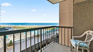 Een balkon met uitzicht op het strand en het zwembad.