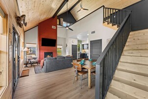 Un amplio salón con chimenea, una mesa de comedor y una escalera.