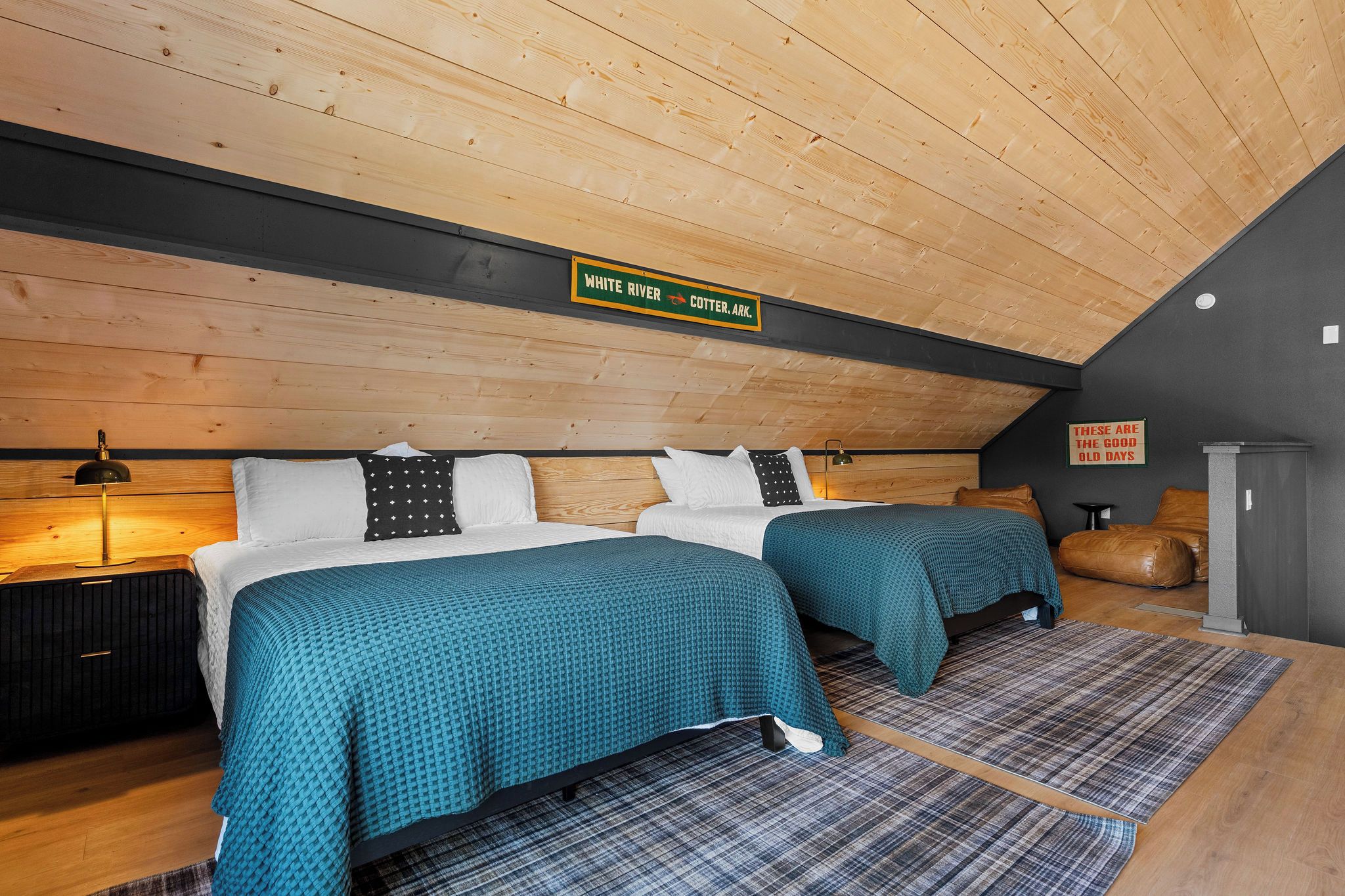 A bedroom with two beds, wooden ceiling, and a sign indicating the location.
