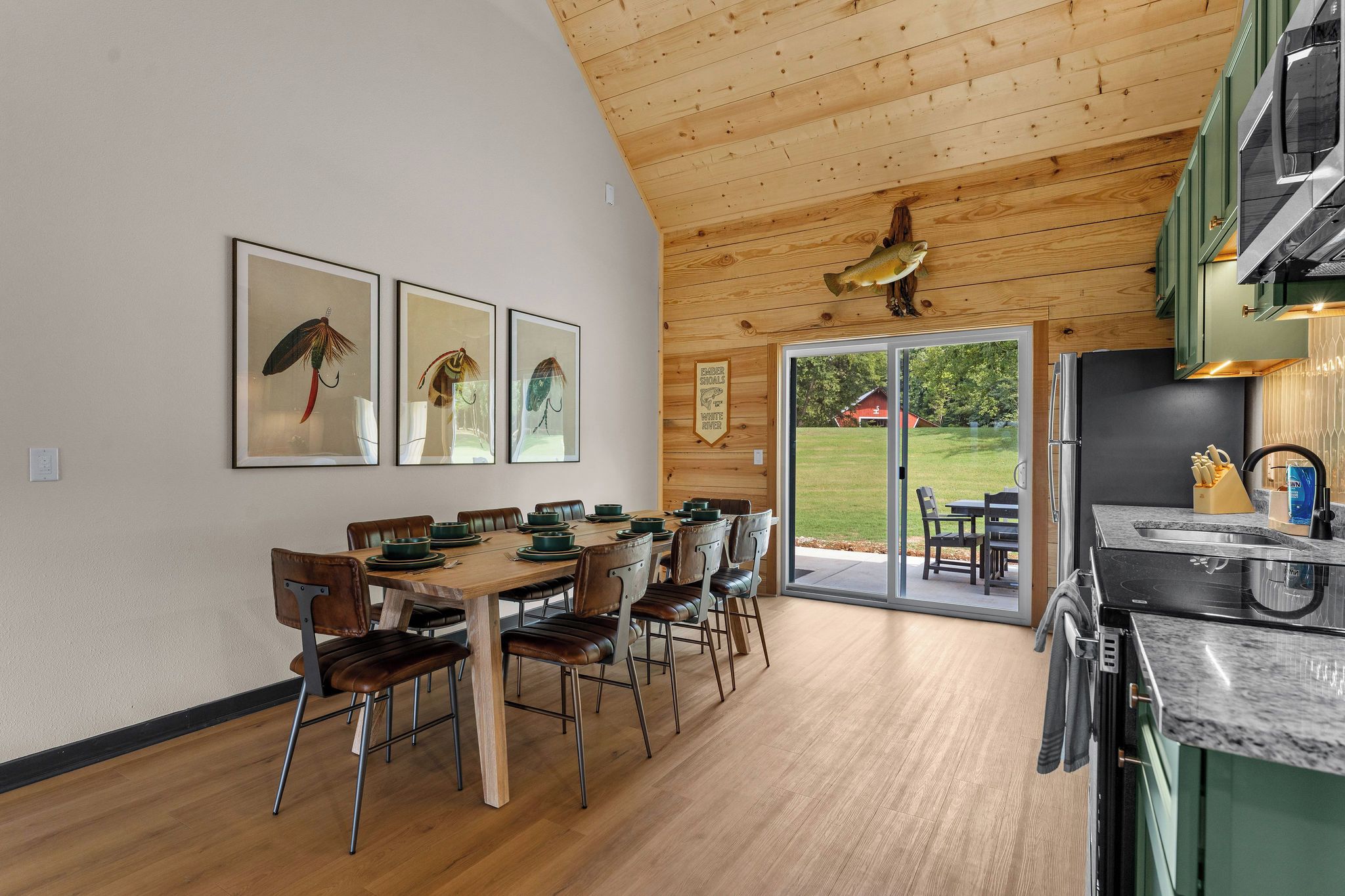 Una cocina moderna con techo de madera, un comedor con mesa y sillas, y vistas al exterior.