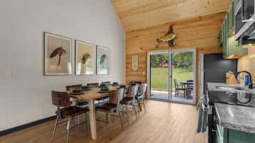 Una cocina moderna con techo de madera, un comedor con mesa y sillas, y vistas al exterior.