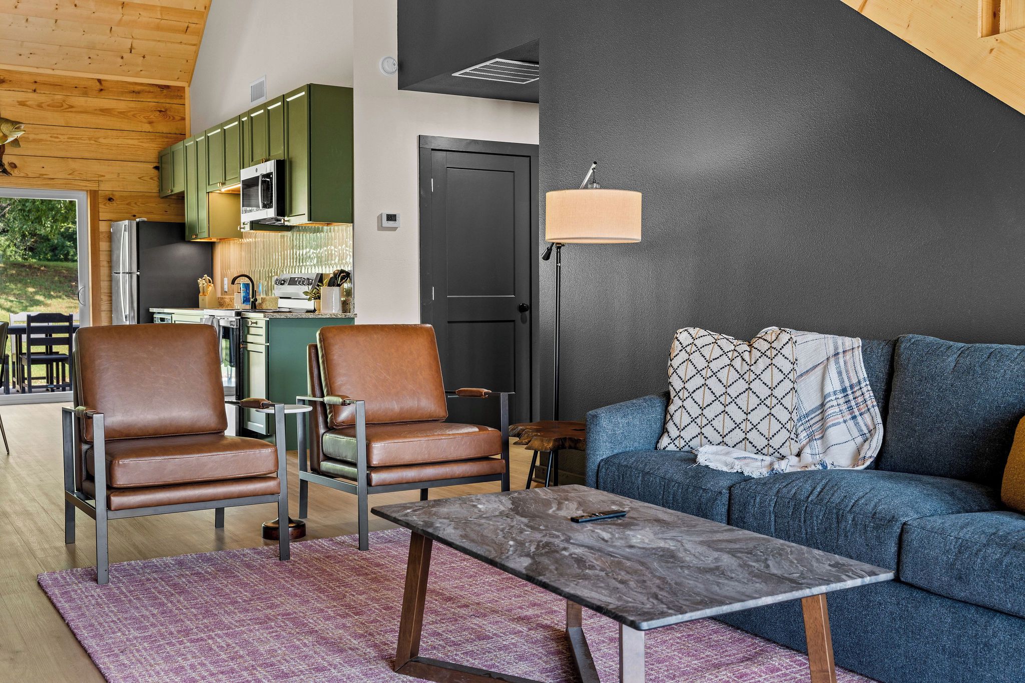 A modern living room with leather chairs, a sofa, and a marble coffee table.