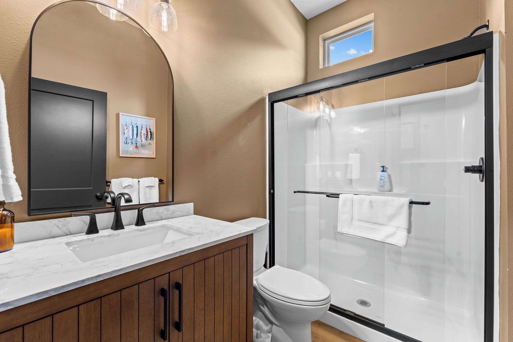 A bathroom with a double sink, a toilet, and a glass-enclosed shower.