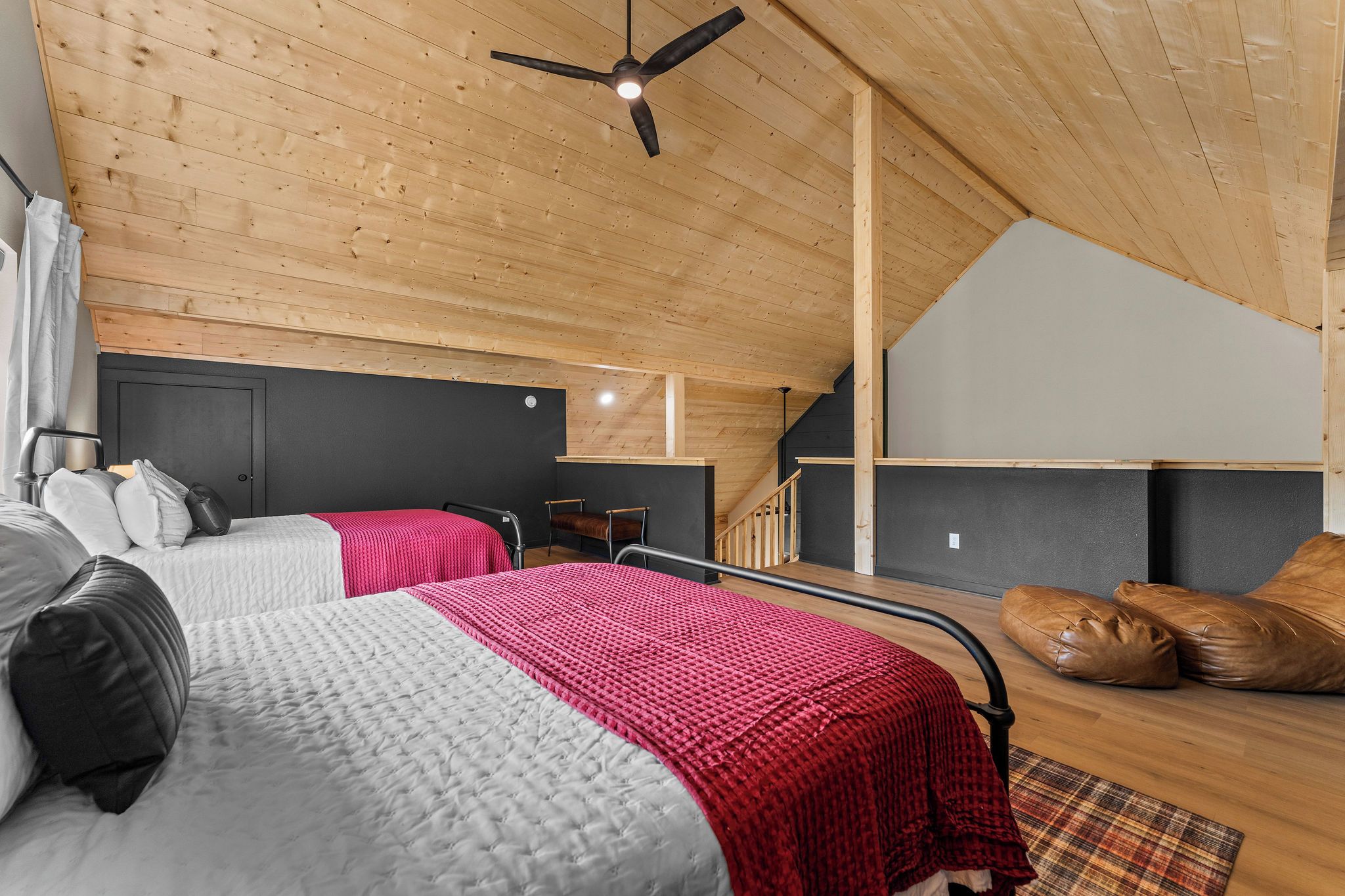Une chambre avec deux lits, un ventilateur de plafond et un escalier menant à un étage supérieur.