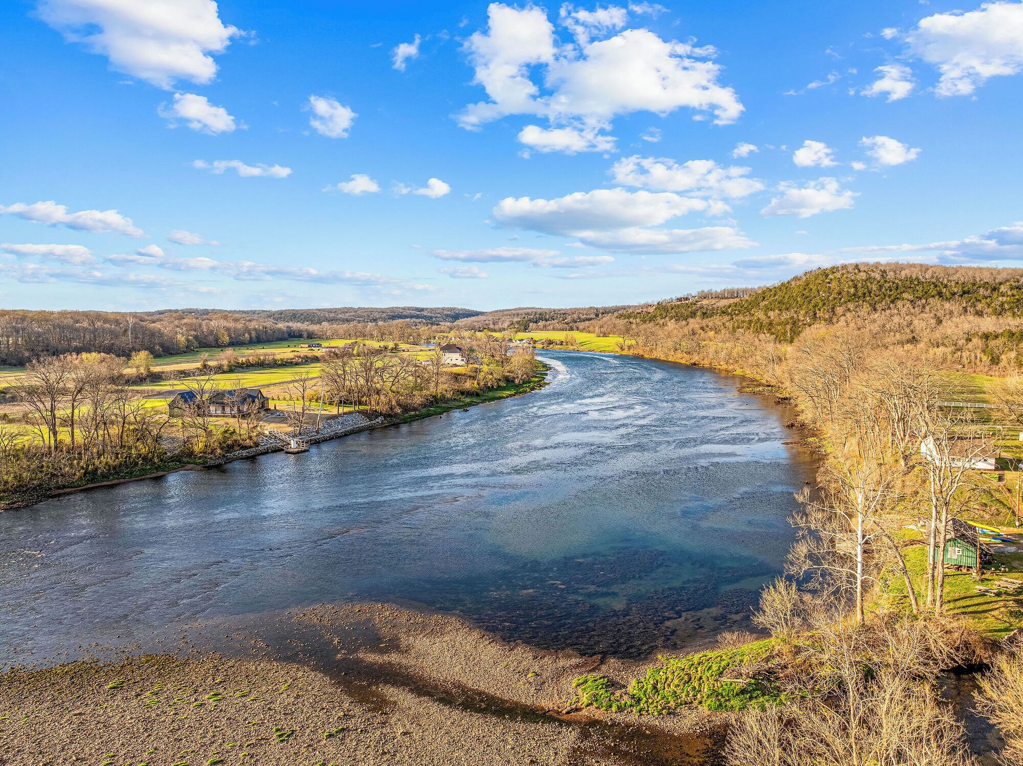 Une rivière qui traverse un paysage rural, avec des maisons et des champs.