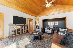 A living room with a television, two armchairs, a sofa, a coffee table, and a fireplace. -  Ember Shoals Resort | On the White River, Cotter AR (Cotter)