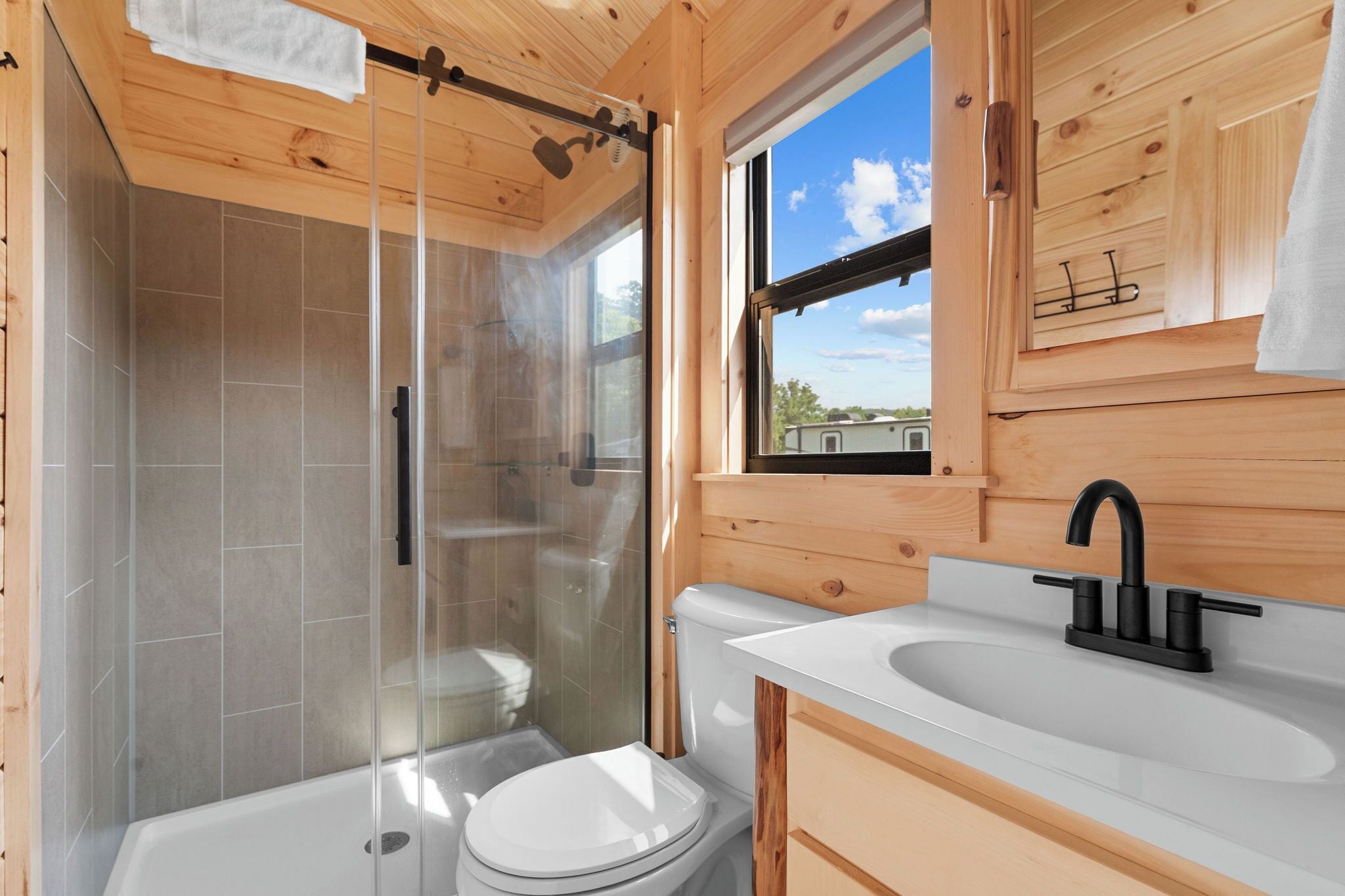 Une salle de bain moderne avec une douche à parois de verre, des toilettes blanches et un lavabo doté d’un robinet noir.