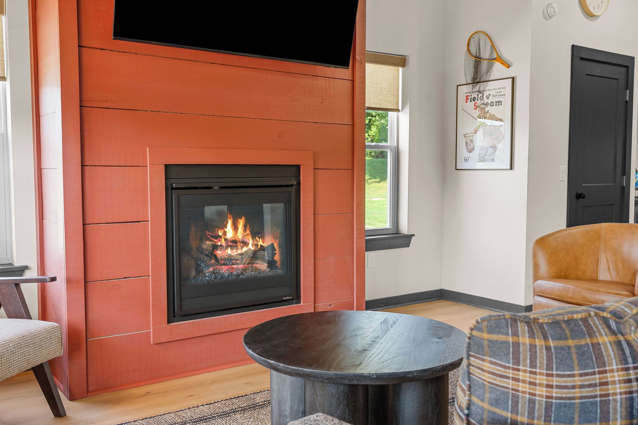 Ein Wohnzimmer mit Kamin, einer Couch, einem Sessel und einem runden Tisch.