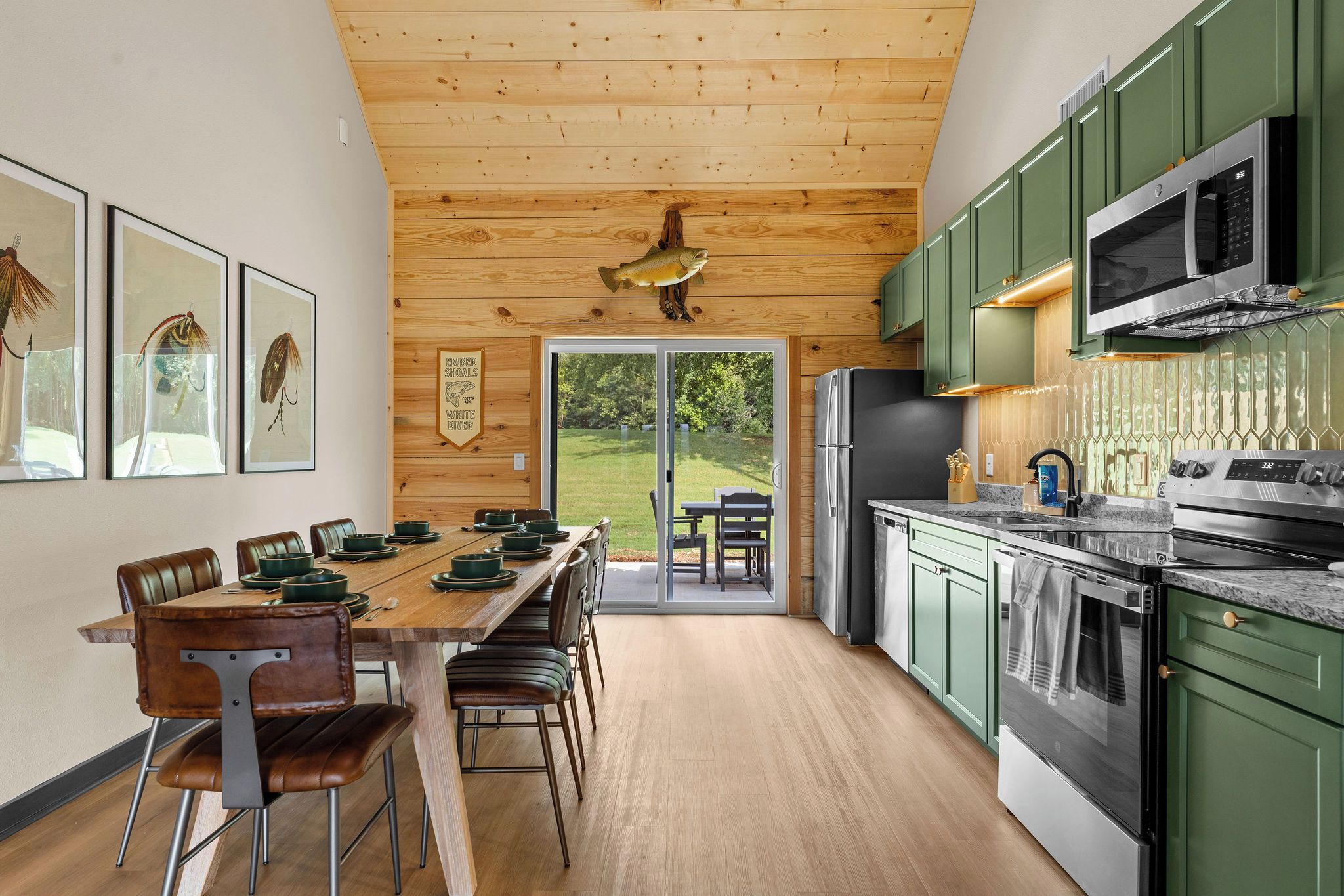 Een moderne keuken met een houten plafond, groene kastjes en een eethoek met een houten tafel en stoelen.