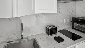 A kitchen with a sink, a toaster, a black tablet, and a microwave. - Brand New Private Guest House (Miami)