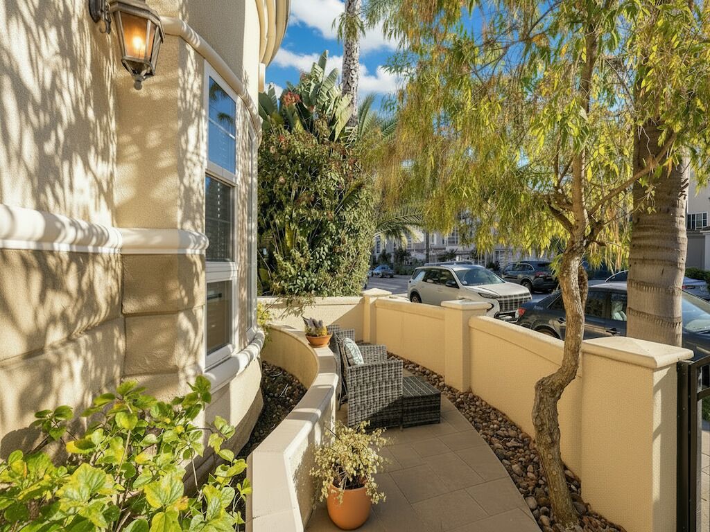 A patio with outdoor seating, a tree, and a view of parked cars.