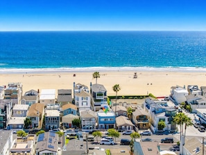 Zona residencial costera con casas, una playa y un cielo azul despejado.