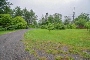A rural road curving through a grassy area with trees and a wooden fence. - Spa & Nature | La Halte (Marsoui)