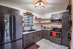 Una cocina moderna con electrodomésticos de acero inoxidable, armarios de madera y salpicadero de azulejos.