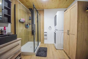 Une cuisine compacte dotée d’une cabine de douche en verre, de meubles en bois et d’un réfrigérateur encastré.
