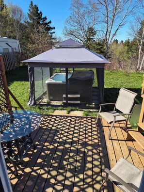 A wooden deck with a glass table and chairs, a hot tub, and a gazebo. - Spa & Nature | La Halte (Marsoui)