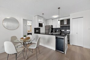 Una cocina moderna con una isla central, armarios blancos y electrodomésticos de acero inoxidable.